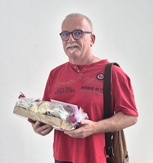 Männliche Person mit einem Präsentkorb zum Jubiläum in den Händen.