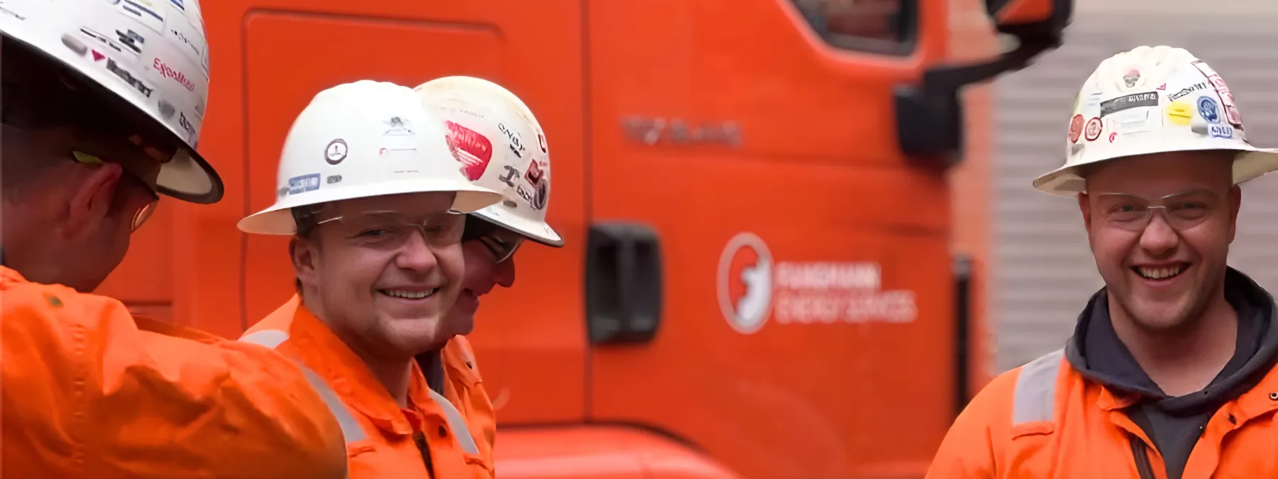 4 Mitarbeiter der Firma Fangmann Energy services in orangen Arbeitsanzügen und weißem Helm