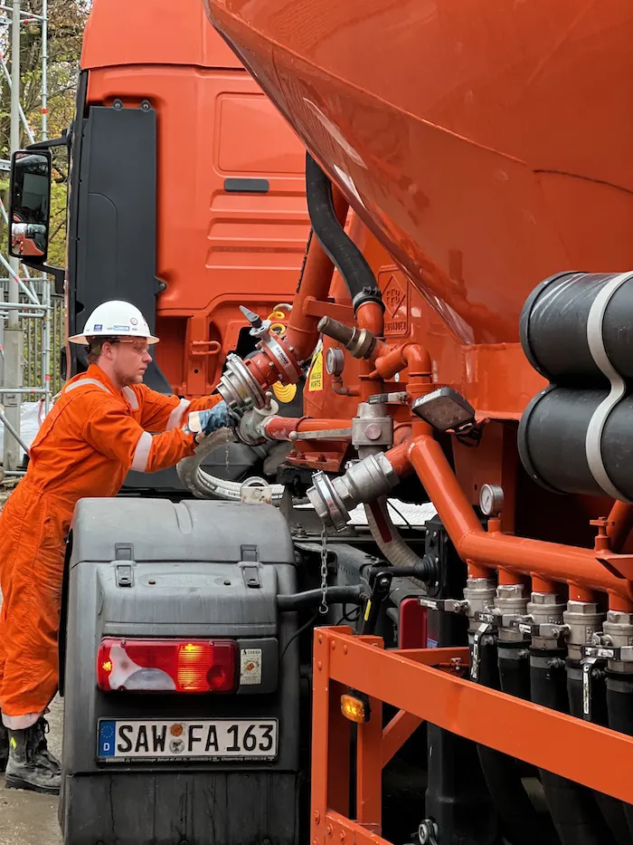 Techniker schraubt ein Verbindungsrohr an einen Pumpwagen an.